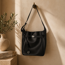 Lataa kuva Galleria-katseluun, Musta GAIA Premium vasikannahkalaukku lämpimässä luonnonvalossa. Elegantti italialainen olkalaukku hopeansävyisillä metalliyksityiskohdilla, minimalistinen quiet luxury -tyyli ja ylellinen sisustustausta.