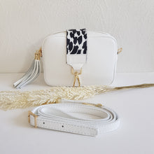 Lataa kuva Galleria-katseluun, ANGIE olkalaukussa on kaksi säädettävää olkahihnaa ja vetoketjukiinnitys. Tupsukoriste toimii vetimenä. Erittäin suosittu crossbody malli. Materiaali: aitoa nahkaa Väri: valkoinen Koko: pituus 20 cm, korkeus 15 cm, syvyys 7 cm. Laukkuun kuuluu kaksi säädettävää olkahihnaa: kapea nahkahihna kullanvärisillä pistolukoilla, leveys 2 cm, säädettävä pituus 128 cm leveä koristeellinen polyesteri/nahka hihna kullanvärisillä pistolukoilla, leveys 5,5 cm, säädettävä pituus max. 128 cm