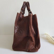 Lataa kuva Galleria-katseluun, Upea CHIARA laukku on tunnetun Bottega Veneta brändin inspiroima malli. Tyylikäs ja tilava laukku on valmistettu aidosta intrecciato punotusta nahasta. Sisällä on vetoketjullinen tilanjakaja sekä vetoketjullinen sivutasku sekä avotasku Väri: ruskea Kantokahvat ja olkahihna on säädettävät. Koko: korkeus 32 cm, leveys 50 cm, syvyys 19 cm Olkahihnan koko: leveys 2 cm, max pituus 125 cm Valmistettu Italiassa.