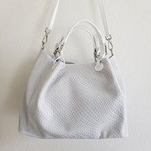 Lataa kuva Galleria-katseluun, Upea CHIARA laukku on tunnetun Bottega Veneta brändin inspiroima malli. Tyylikäs ja tilava laukku on valmistettu aidosta intrecciato punotusta nahasta. Sisällä on vetoketjullinen tilanjakaja sekä vetoketjullinen sivutasku sekä avotasku. Väri: valkoinen Kantokahvat ja olkahihna on säädettävät. Koko: korkeus 32 cm, leveys 50 cm, syvyys 19 cm Olkahihnan koko: leveys 2 cm, max pituus 125 cm Valmistettu Italiassa.