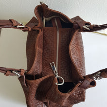 Lataa kuva Galleria-katseluun, Upea CHIARA laukku on tunnetun Bottega Veneta brändin inspiroima malli. Tyylikäs ja tilava laukku on valmistettu aidosta intrecciato punotusta nahasta. Sisällä on vetoketjullinen tilanjakaja sekä vetoketjullinen sivutasku sekä avotasku   Väri: ruskea  Kantokahvat ja olkahihna on säädettävät.  Koko: korkeus 32 cm, leveys 50 cm, syvyys  19  cm  Olkahihnan koko: leveys  2 cm, max pituus 125   cm  Valmistettu Italiassa.
