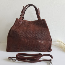 Lataa kuva Galleria-katseluun, Upea CHIARA laukku on tunnetun Bottega Veneta brändin inspiroima malli. Tyylikäs ja tilava laukku on valmistettu aidosta intrecciato punotusta nahasta. Sisällä on vetoketjullinen tilanjakaja sekä vetoketjullinen sivutasku sekä avotasku   Väri: ruskea  Kantokahvat ja olkahihna on säädettävät.  Koko: korkeus 32 cm, leveys 50 cm, syvyys  19  cm  Olkahihnan koko: leveys  2 cm, max pituus 125   cm  Valmistettu Italiassa.
