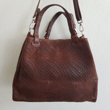 Lataa kuva Galleria-katseluun, Upea CHIARA laukku on tunnetun Bottega Veneta brändin inspiroima malli. Tyylikäs ja tilava laukku on valmistettu aidosta intrecciato punotusta nahasta. Sisällä on vetoketjullinen tilanjakaja sekä vetoketjullinen sivutasku sekä avotasku   Väri: ruskea  Kantokahvat ja olkahihna on säädettävät.  Koko: korkeus 32 cm, leveys 50 cm, syvyys  19  cm  Olkahihnan koko: leveys  2 cm, max pituus 125   cm  Valmistettu Italiassa.
