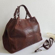Lataa kuva Galleria-katseluun, Upea CHIARA laukku on tunnetun Bottega Veneta brändin inspiroima malli. Tyylikäs ja tilava laukku on valmistettu aidosta intrecciato punotusta nahasta. Sisällä on vetoketjullinen tilanjakaja sekä vetoketjullinen sivutasku sekä avotasku Väri: ruskea  Kantokahvat ja olkahihna on säädettävät. Koko: korkeus 32 cm, leveys 50 cm, syvyys 19 cm. Olkahihnan koko: leveys 2 cm, max pituus 125 cm  Valmistettu Italiassa.
