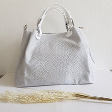Lataa kuva Galleria-katseluun, Upea CHIARA laukku on tunnetun Bottega Veneta brändin inspiroima malli. Tyylikäs ja tilava laukku on valmistettu aidosta intrecciato punotusta nahasta. Sisällä on vetoketjullinen tilanjakaja sekä vetoketjullinen sivutasku sekä avotasku.  Väri: valkoinen  Kantokahvat ja olkahihna on säädettävät.  Koko: korkeus 32 cm, leveys 50 cm, syvyys  19  cm  Olkahihnan koko: leveys  2 cm, max pituus 125   cm  Valmistettu Italiassa.

